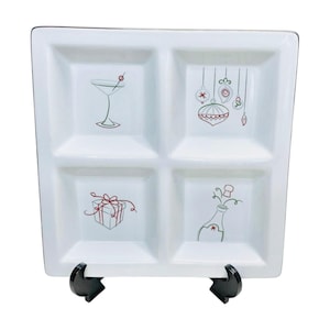 May include: White ceramic serving tray with four divided sections. Each section features a festive holiday design: a martini glass, Christmas baubles, a gift box, and a champagne bottle.