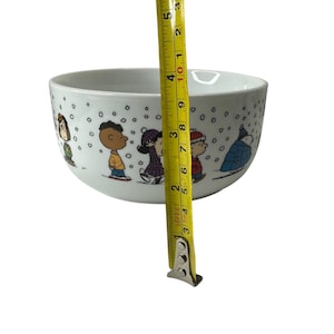 Puede incluir: Cuenco de cer&aacute;mica blanco con una escena invernal con personajes de dibujos animados. El cuenco mide aproximadamente 7,6 cm de alto y 12,7 cm de di&aacute;metro. El cuenco tiene forma redondeada y est&aacute; decorado con un patr&oacute;n repetido de copos de nieve.