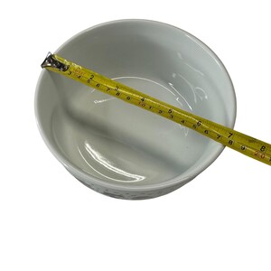 Puede incluir: Un cuenco de cer&aacute;mica blanca con una cinta m&eacute;trica amarilla en la parte superior. La cinta muestra una medida de aproximadamente 20 cm de di&aacute;metro. El cuenco tiene un dise&ntilde;o sencillo y limpio.