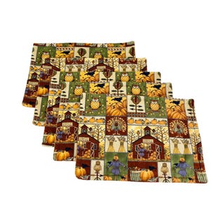 Könnte beinhalten: Set aus fünf rechteckigen Tischsets mit einem Patchwork-Design, das Herbstszenen zeigt. Die Tischsets zeigen Bilder von Kürbissen, Eulen, Vogelscheuchen und Scheunen in Orange-, Grün-, Braun- und Gelbtönen.