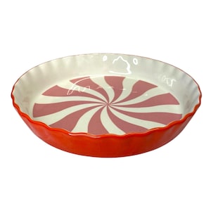 May include: A red and white ceramic pie dish with a swirl pattern. The dish has a scalloped edge.