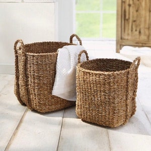 Peut inclure: Deux paniers de rangement en jonc de mer tressé avec des poignées. Le plus grand panier est brun et contient une serviette blanche. Le plus petit panier est d'un brun plus clair.