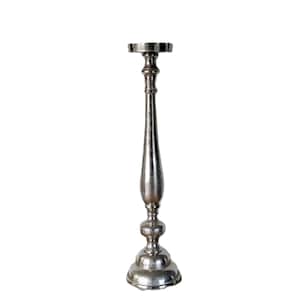 May include: A silver candlestick holder with a round base and a decorative, elongated stem. The top of the holder is a flat, circular platform. The candlestick is made of metal and has a textured finish. The height is approximately 30 cm.