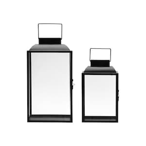 Könnte beinhalten: Zwei schwarze Metall-Laternen mit Glasplatten. Die größere Laterne ist höher als die kleinere.