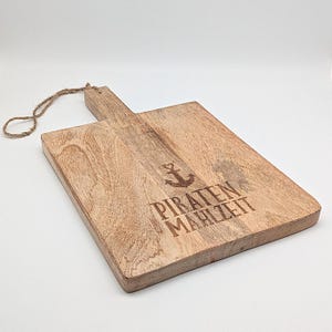 May include: A wooden cutting board with a rope handle. The board is engraved with an anchor and the text "PIRATEN MAHLZEIT".