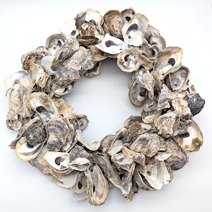 Peut inclure: Une couronne circulaire composée de nombreuses coquilles d'huîtres, présentant une esthétique côtière naturelle. Les coquilles varient en couleur, du blanc cassé au brun et gris, créant un design texturé et organique. Idéal pour la décoration sur le thème de la plage.