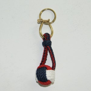 Peut inclure: Un porte-clés en nœud marin rouge, blanc et bleu avec un anneau en laiton.
