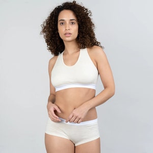 K&ouml;nnte beinhalten: Ein wei&szlig;er Sport-BH und ein passendes Unterw&auml;sche-Set. Der BH hat einen Racerback-Stil und die Unterw&auml;sche hat einen Boy-Short-Stil.