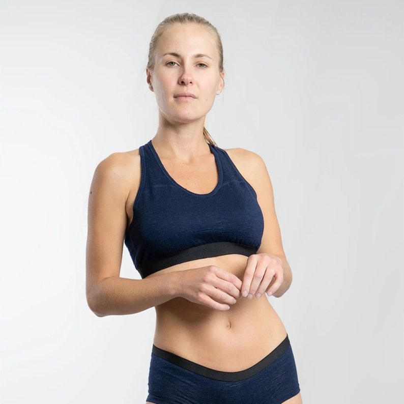 K&ouml;nnte beinhalten: Ein marineblauer Sport-BH mit Racerback-Design und einem schwarzen elastischen Band. Der BH ist aus einem weichen, atmungsaktiven Material gefertigt.