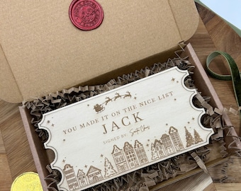 May include: A wooden ticket with the text "You made it on the nice list Jack Signed by: Santa Claus" and a small illustration of Santa Claus in a sleigh with reindeer flying over a small town.