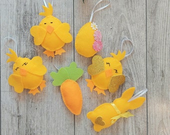 May include: A set of six felt Easter decorations, including a carrot, a bunny, and four chicks. The decorations are yellow, orange, and pink.