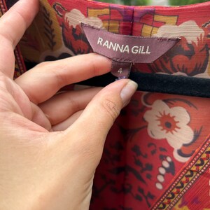 May include: A red, orange, and yellow floral print dress with a brown tag that reads "Ranna Gill" and a size 4 label.