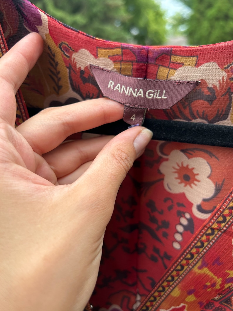 May include: A red, orange, and yellow floral print dress with a brown tag that reads "Ranna Gill" and a size 4 label.