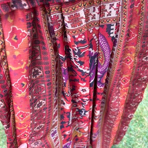 May include: Red, orange, and purple patterned fabric with a geometric design. The fabric is pleated and has a sheer texture.