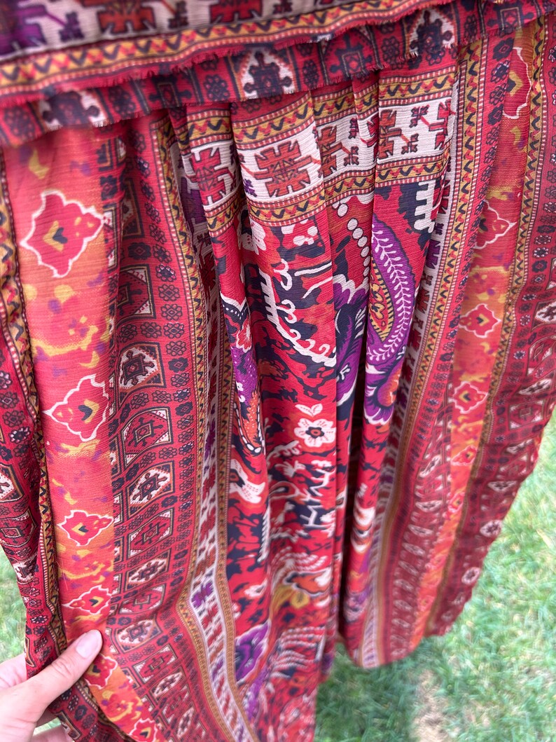 May include: Red, orange, and purple patterned fabric with a geometric design. The fabric is pleated and has a sheer texture.