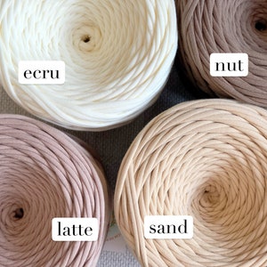 May include: Four spools of cotton rope in various shades of beige, from white to brown. The spools are labelled "ecru", "nut", "sand", and "latte".