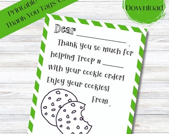 Può includere: Etichette o biglietti di ringraziamento stampabili da 10,16 cm x 12,7 cm con un bordo a strisce verde e bianco. La carta presenta un'immagine disegnata a mano di due biscotti con gocce di cioccolato, uno dei quali è stato morso. Il testo sulla carta recita: "Caro/a, Grazie mille per aver aiutato la truppa # con il tuo ordine di biscotti! Goditi i tuoi biscotti! Da parte di,"