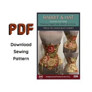 May include: A sewing pattern for a triple-tie under-bust corset. The pattern features a floral design on a beige background. The text "RABBIT & HAT SEWING PATTERN Making magic one stitch at a time... TRIPLE-TIE UNDER-BUST CORSET" is printed on the pattern. The text "Designed and Printed in the U.S.A. 220" is also printed on the pattern.