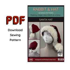 May include: A sewing pattern for a Santa hat. The pattern includes instructions for making a hat with a red felt base and a white faux fur trim. The pattern is designed and printed in the U.S.A. and has the number 5123 printed on it.