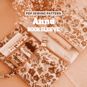 Könnte beinhalten: Eine Bücherhülle mit floralem Muster mit dem Text "Anna BOOKSLEEVE" und "PDF SEWING PATTERN". Die Bücherhülle ist geöffnet und zeigt Stifte, ein Notizbuch und andere Schreibwaren. Die Farbpalette ist hauptsächlich braun und cremefarben.