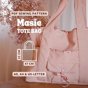 Könnte beinhalten: Schnittmuster für eine rosafarbene Cord-Tote-Bag mit der Aufschrift "Masie TOTE BAG". Die Tasche hat eine Tasche und einen floralen Besatz. Die Tasche ist 47 cm breit und 31 cm hoch. Das Muster ist in A0, A4 und US-LETTER erhältlich.