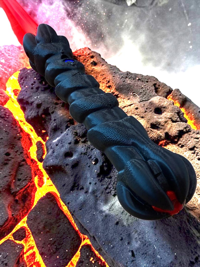 May include: A black, textured, dragon-claw-shaped object with a blue gem and red accents. The object is set against a backdrop of volcanic rock and lava, creating a fantasy or sci-fi theme.