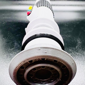 Puede incluir: Un sable de luz blanco con un mango negro y una punta plateada. El sable de luz tiene una serie de anillos negros alrededor del mango y una serie de peque&ntilde;os agujeros alrededor de la punta.