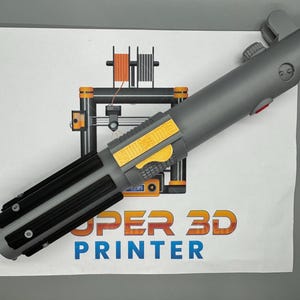 May include: A gray and black lightsaber prop with a yellow and black detail on the handle. The lightsaber is on a white surface with a 3D printer illustration and the text "SUPER 3D PRINTER".