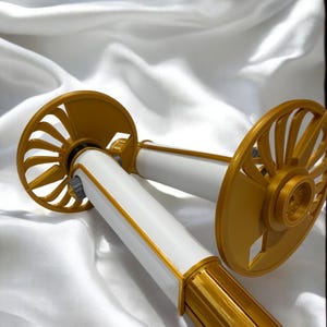 K&ouml;nnte beinhalten: Zwei dekorative, gold-wei&szlig; Objekte mit einem f&auml;cherartigen Design. Die zylindrischen wei&szlig;en K&ouml;rper sind mit Gold akzentuiert. Der Hintergrund ist ein wei&szlig;er, seidiger Stoff.