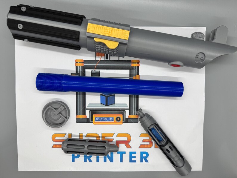 May include: A 3D printed lightsaber, a blue plastic tube, a gray plastic cap, a gray plastic nozzle, and a gray plastic tube with a blue plastic insert. The items are on a white surface with the text "SUPER 3D PRINTER" printed on it.