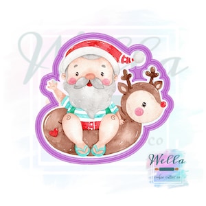 Puede incluir: Un cortador de galletas de acuarela con Papá Noel en un flotador con un reno. Papá Noel lleva un gorro rojo, una camisa a rayas y chanclas. El reno tiene una nariz rosa y cuernos marrones. El cortador está delineado en morado.