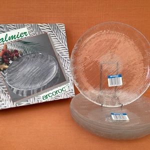 Peut inclure: Un ensemble de six assiettes en verre transparent avec une surface texturée. Les assiettes sont empilées les unes sur les autres. Les assiettes sont étiquetées "Palmier" et "arcoloc".