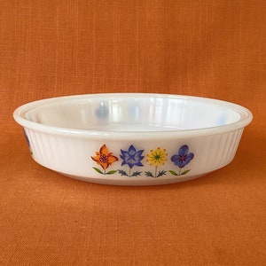 May include: White ceramic pie dish with a floral design. The flowers are orange, blue, yellow, and purple.