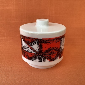 May include: A white ceramic sugar bowl with a lid. The bowl has a geometric pattern in black and red.
