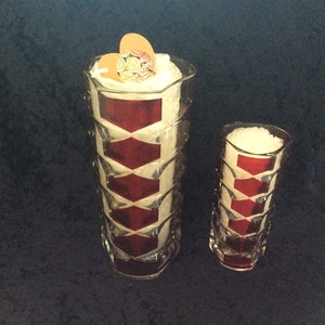 Può includere: Due vasi di vetro trasparente con un motivo geometrico. Il vaso più grande ha un motivo rosso e bianco e il vaso più piccolo ha un motivo rosso e bianco. Entrambi i vasi sono su uno sfondo blu scuro.