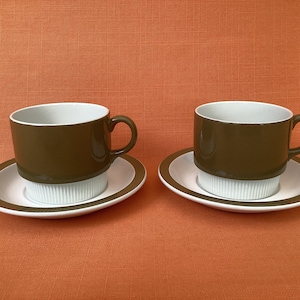 May include: Two brown and white teacups and saucers. The cups have a brown band around the top and a white band around the bottom. The saucers have a brown band around the edge and a white centre.