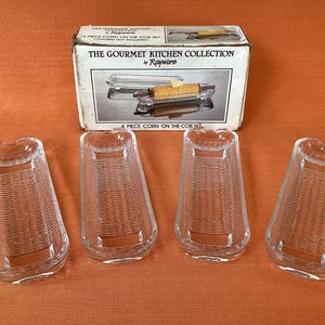 Könnte beinhalten: Ein vierteiliges Maiskolben-Set aus der Gourmet Kitchen Collection von Rayware. Das Set enthält vier transparente Glashalter mit gewebter Textur und eine Box mit einem Bild des Sets. Auf der Box steht "4 Piece Corn on the Cob Set".