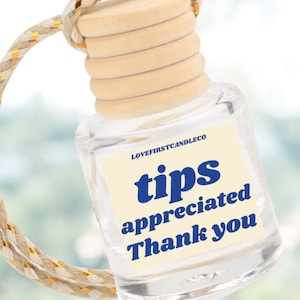 May include: A clear glass bottle with a wooden cap and a white label that says "tips appreciated thank you" in blue text. The bottle is hanging from a gold and beige string.
