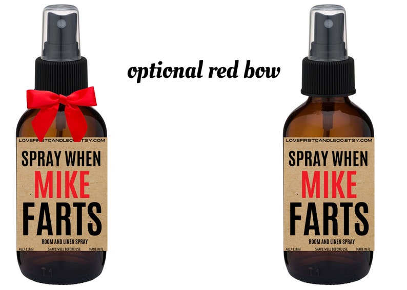 May include: Two brown glass spray bottles with a brown paper label that says "SPRAY WHEN MIKE FARTS" in black and red text. The label also says "ROOM AND LINEN SPRAY" in smaller black text. The bottles have black spray tops and are tied with a red bow.
