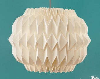 Puede incluir: Una lámpara colgante de estilo origami blanca cuelga de un techo contra una pared azul turquesa. Una rama blanca con hojas se encuentra sobre un cubo azul turquesa.