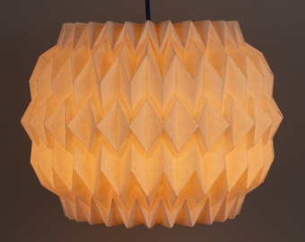 Könnte beinhalten: Eine weiße Papier-Pendelleuchte mit geometrischem Design. Die Leuchte hängt an einem schwarzen Kabel.