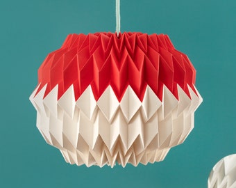 Könnte beinhalten: Ein weißer und roter Lampenschirm aus Origami-Papier hängt von der Decke über einer blaugrünen Oberfläche. Eine kleinere, weiße Kugel aus Origami-Papier liegt auf der Oberfläche.