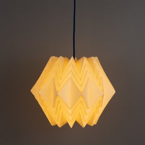 Puede incluir: Una l&aacute;mpara colgante de estilo origami blanca con un dise&ntilde;o geom&eacute;trico. La luz est&aacute; encendida y proyecta un brillo c&aacute;lido.