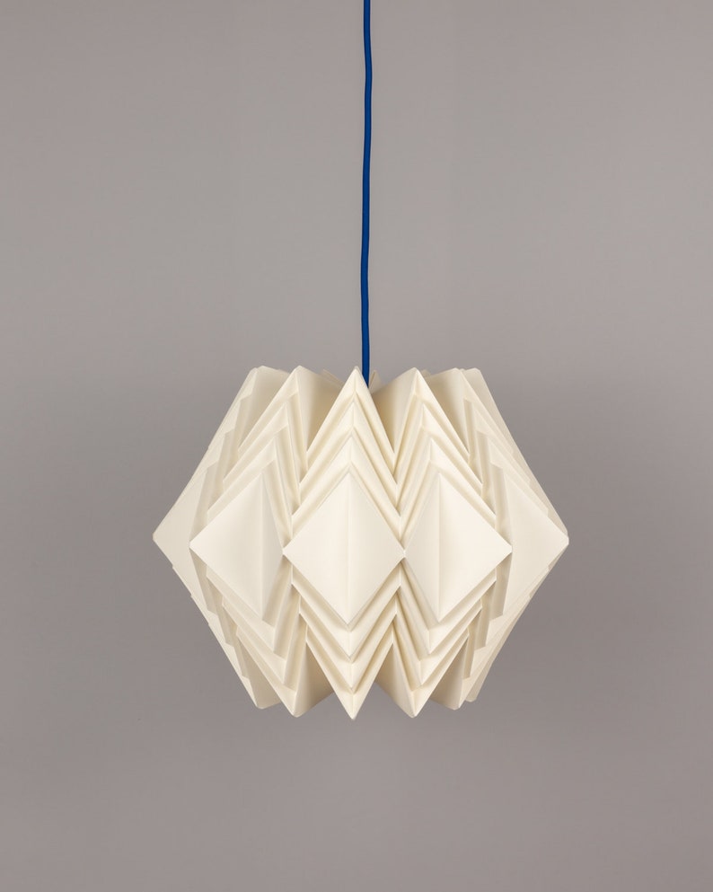 Puede incluir: Una l&aacute;mpara colgante de estilo origami blanca con un cable azul que cuelga del techo.