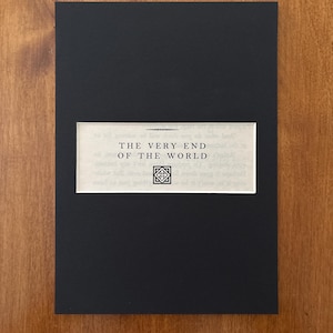 Op de afbeelding: Een zwarte boekomslag met de titel "THE VERY END OF THE WORLD" in witte tekst. De titel staat op een rechthoekig, gebroken wit label. Daaronder staat een klein, symmetrisch ontwerp.