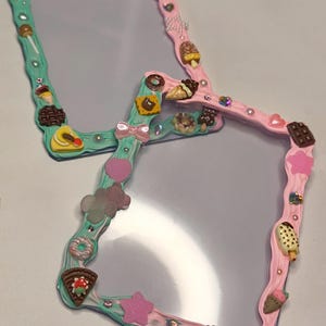 May include: Two rectangular mirrors with frames decorated in textured pink and mint green material. The frames feature miniature charms including ice cream cones, donuts, waffles, chocolate bars, stars, hearts, and small iridescent rhinestones.