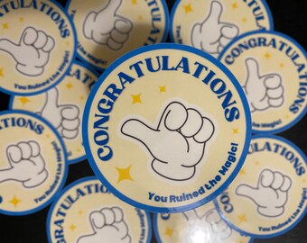 May include: Round stickers with a light yellow background and a blue border. The stickers feature a cartoon hand giving a thumbs-up and the text "CONGRATULATIONS" in blue. The phrase "You Ruined the Magic!" is also included.