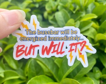 May include: A white sticker with the text "The bussbar will be energized immediately... BUT WILL IT?" in blue and red, with yellow lightning bolt accents. The sticker is held against a background of green leaves.