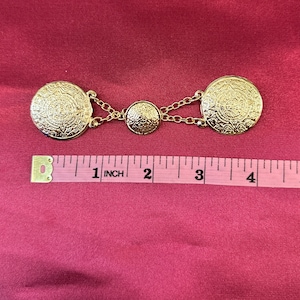 May include: Gold tone metal chain with three round decorative medallions. The medallions have a detailed design and measure approximately 1 inch in diameter.