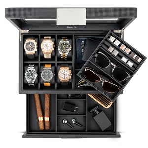 May include: A black watch and accessory organizer with a carbon fiber pattern. The top section holds six watches, while the drawer contains cigars, sunglasses, cufflinks, and grooming items. The brand name "Glenor Co" is visible.